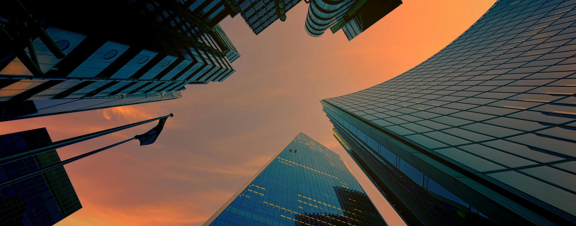 Low angle view of modern skyscrapers against a vibrant sunset sky.